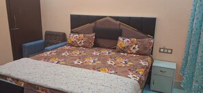 Quarto com cama, mesa de cabeceira, guarda-roupa e cortina.