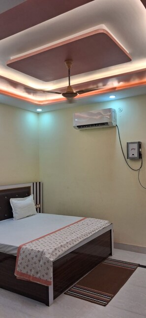 Quarto com cama, ar condicionado e ventilador de teto.