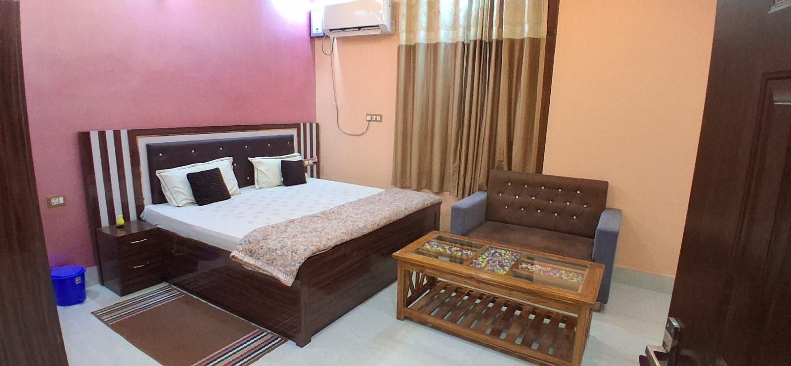 Quarto com cama, sofá, mesa de centro e ar condicionado.