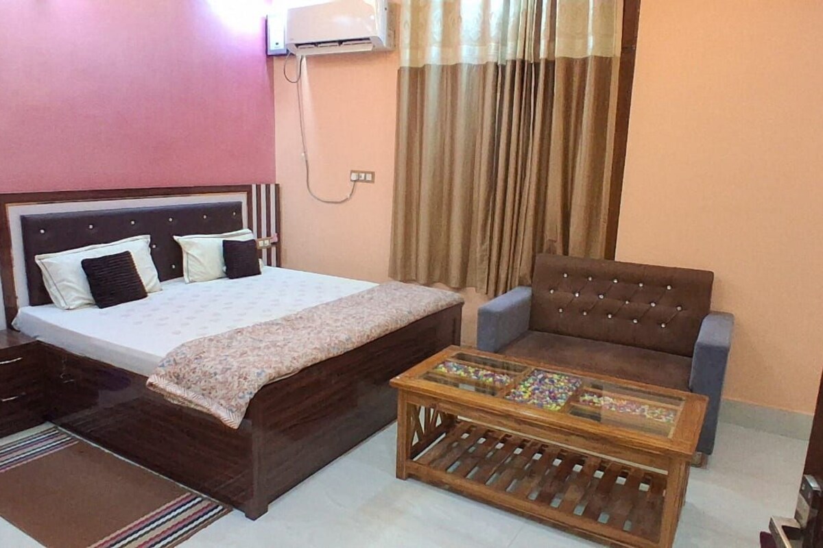 Quarto com cama, sofá, mesa de centro e ar condicionado.