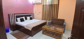 Quarto com cama, sofá, mesa de centro e ar condicionado.