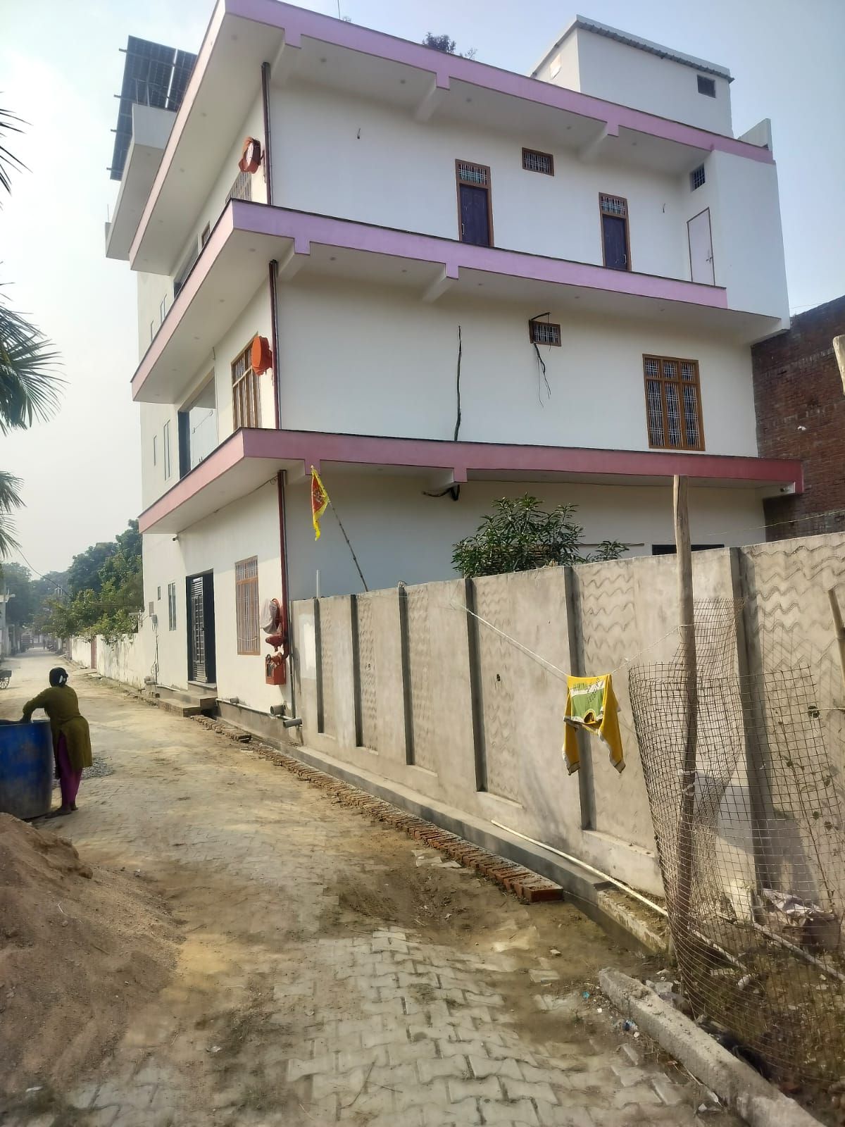 Un immeuble résidentiel à plusieurs étages doté de balcons, une rue pavée et une personne portant un grand récipient.
