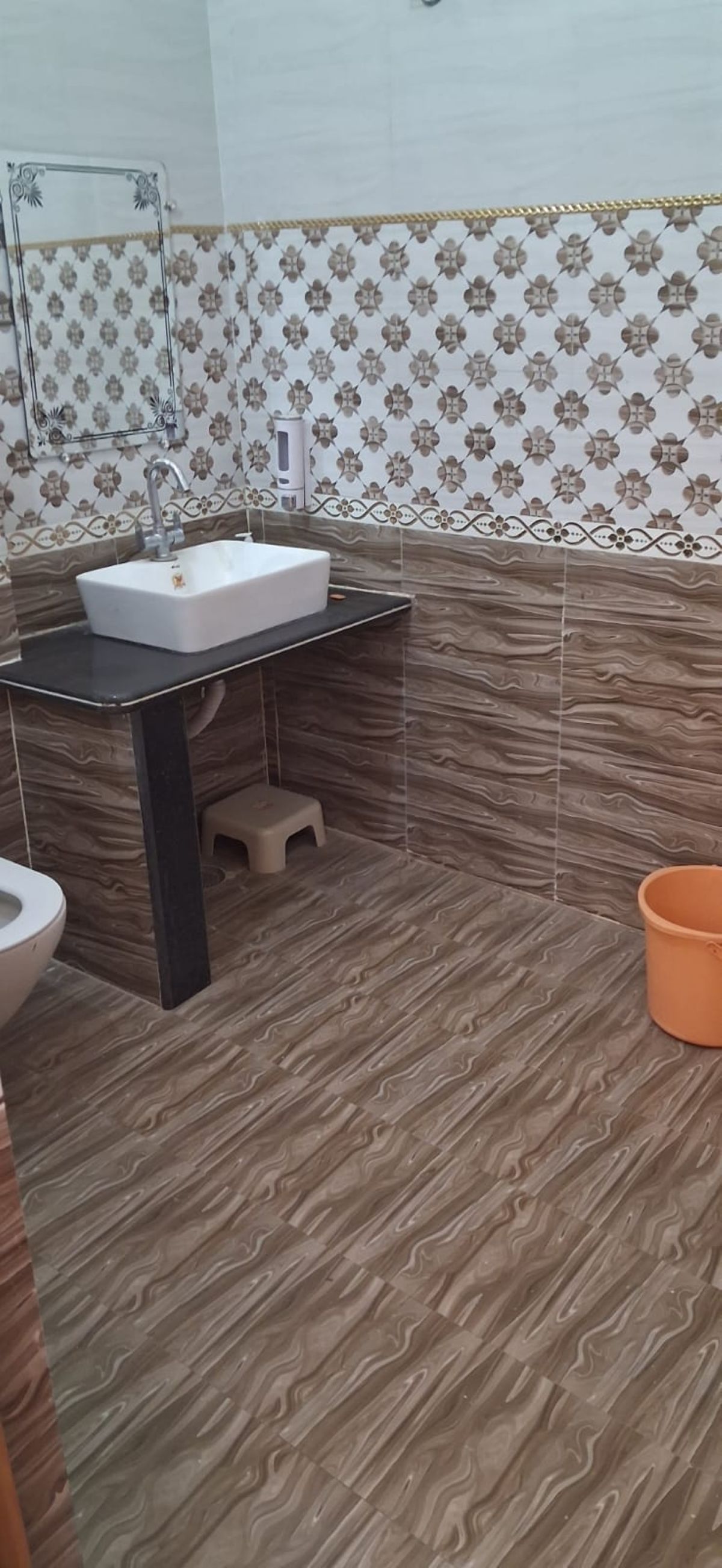 Casa de banho com pia, sanita e um pequeno banquinho.