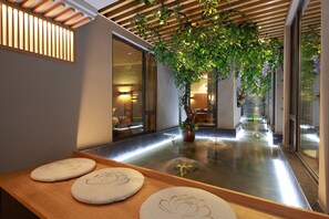 Interior moderno com um elemento de água, teto de madeira e vista para um quarto com cama.