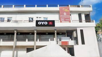 Un bâtiment d'hôtel avec une enseigne indiquant « OYO Hotel Yash Raj Palace » et une banderole promotionnelle offrant une réduction de 50 % sur le stationnement.