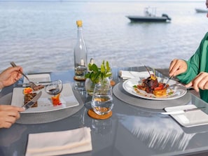 A dining table with plates of food, a bottle, and a glass of water. - Mantis Soanambo Hotel and Spa Sainte Marie (Nosy Boraha)