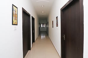 Un pasillo con puertas a ambos lados, suelo de baldosas e iluminación empotrada en el techo.