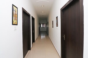 Un pasillo con puertas a ambos lados, suelo de baldosas e iluminación empotrada en el techo.