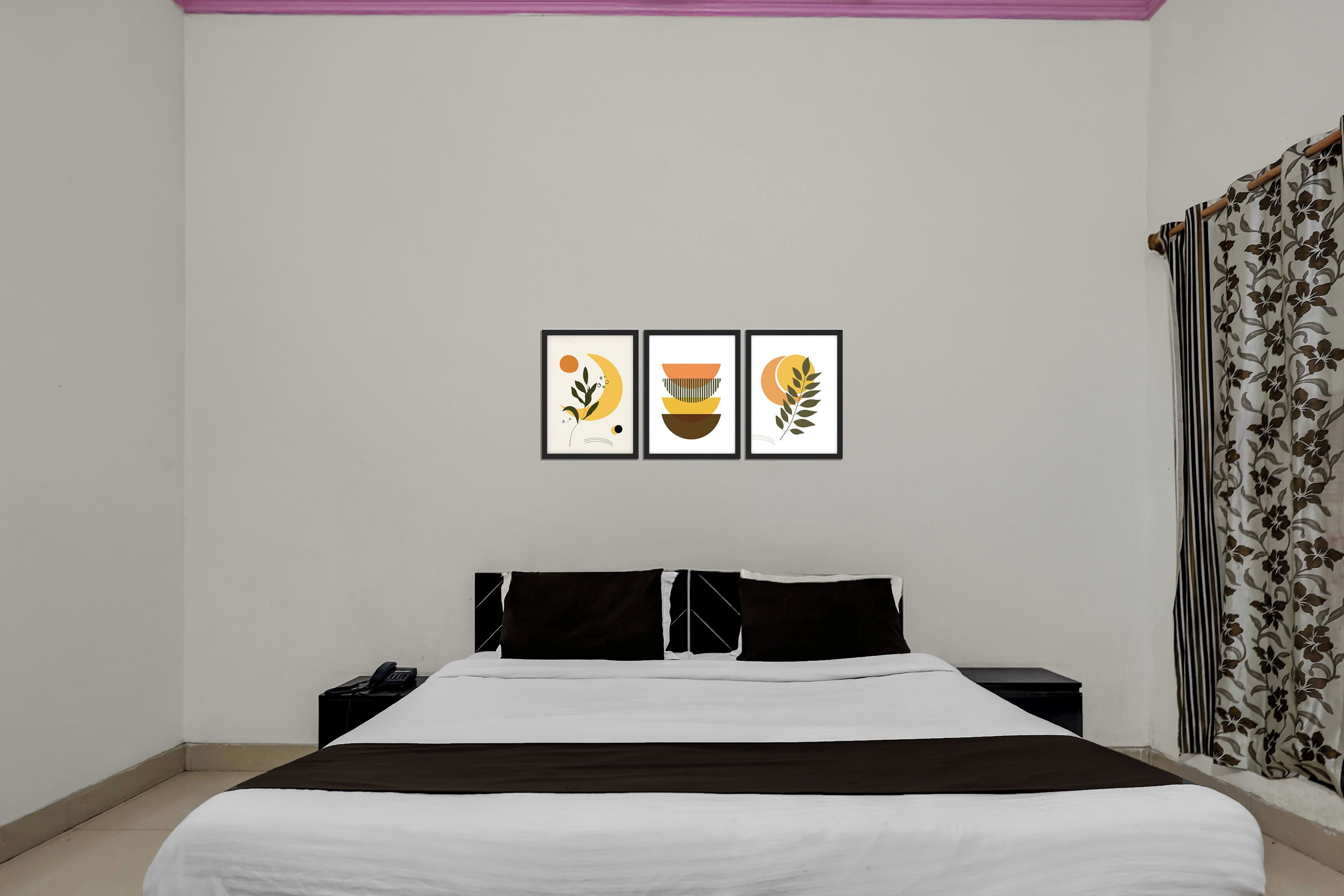 Un dormitorio con cama, mesitas de noche y tres cuadros enmarcados en la pared.