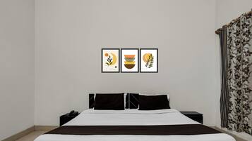 Un dormitorio con cama, mesitas de noche y tres cuadros enmarcados en la pared.