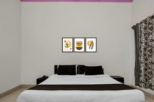 Un dormitorio con cama, mesitas de noche y tres cuadros enmarcados en la pared.