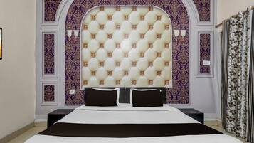 Un dormitorio con cabecera capitonada, cama con ropa blanca y pared con estampado floral.