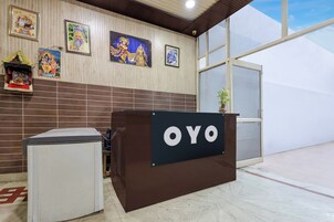 Una recepción con el nombre 'OYO' y una pared de azulejos con motivos religiosos.