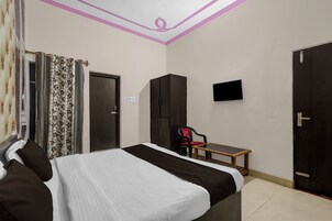 Un dormitorio con cama, armario, escritorio, silla y televisor.