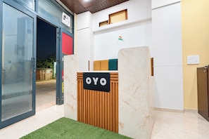 A reception desk with a sign that reads 'OYO' in a modern interior with a glass door entrance and a small flag on the wall. - Hotel O Shree Hotel (Rewari)