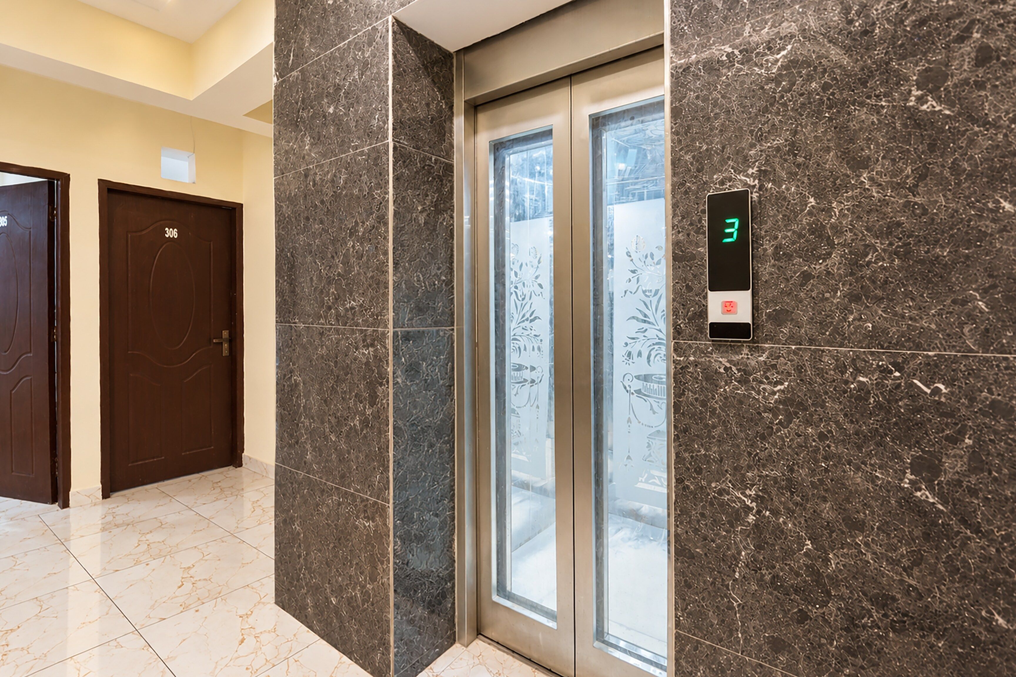 An elevator with a digital display showing the number 3, adjacent to a door with the number 306.
