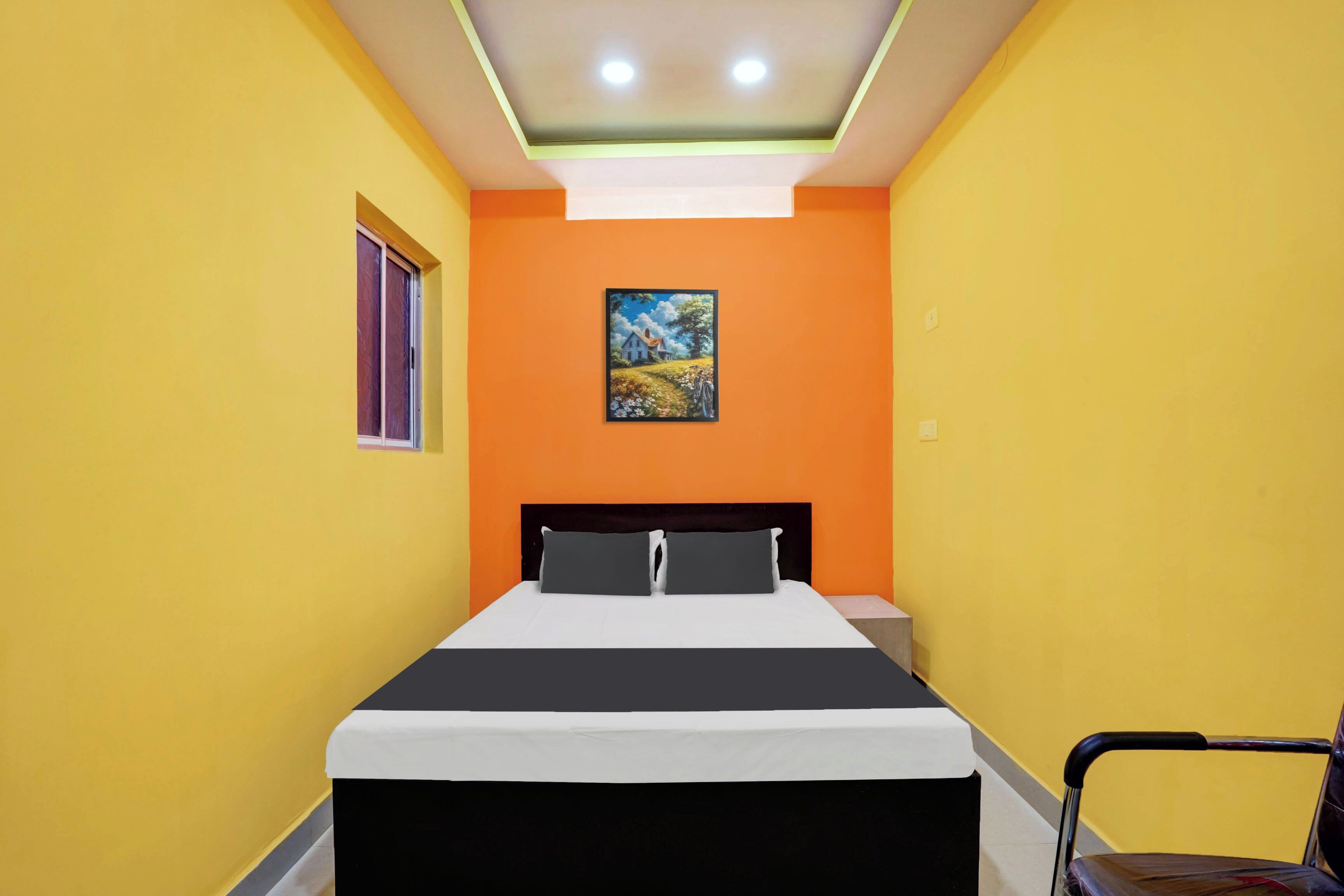 A room with a bed, a chair, and a painting on the wall.