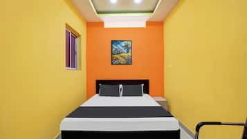A room with a bed, a chair, and a painting on the wall.