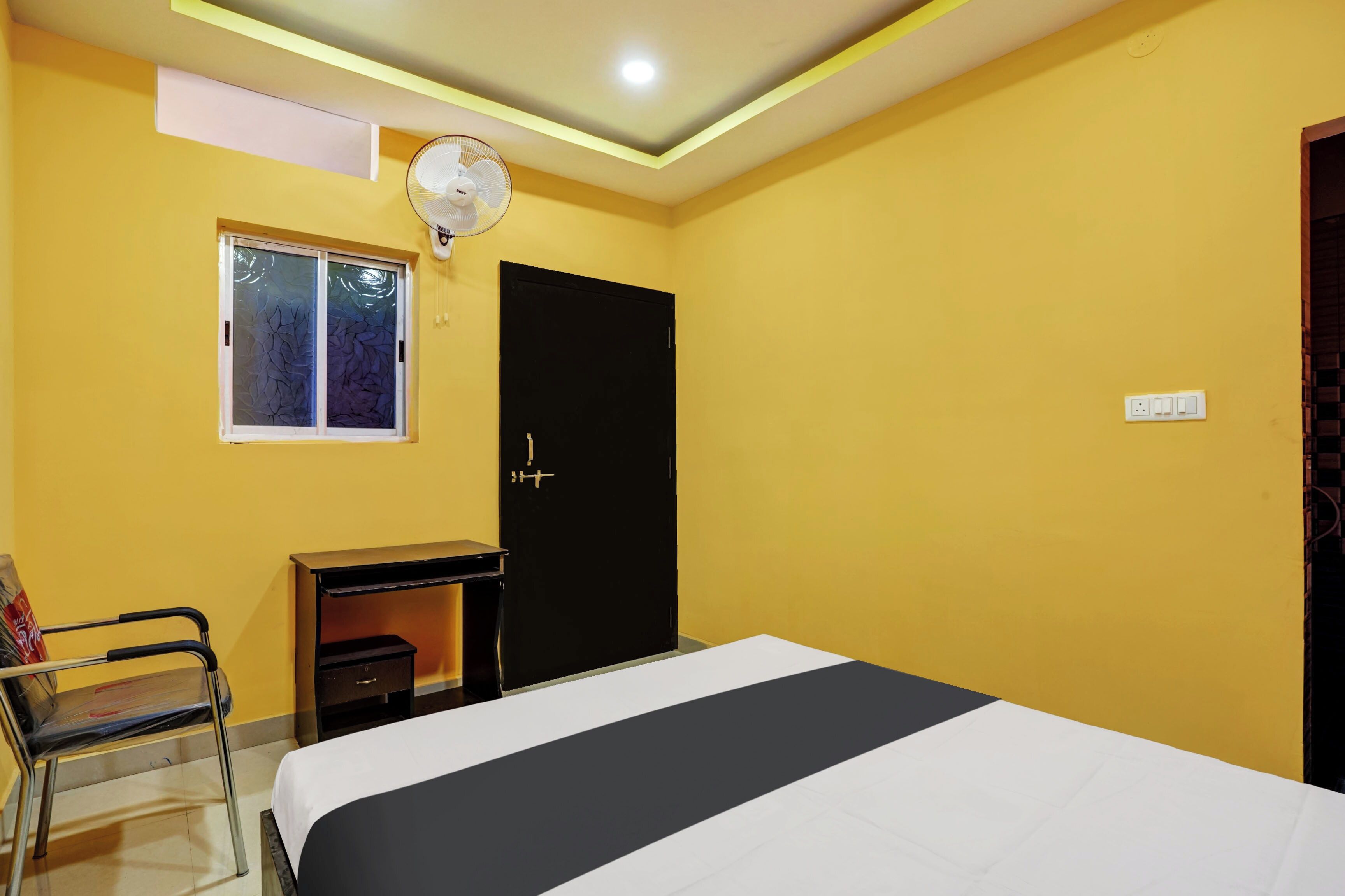 Quarto com cama, escrivaninha, cadeira, janela e porta.