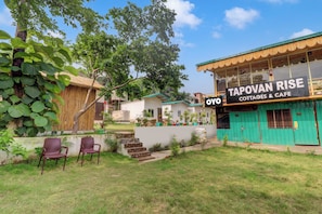 A property with a sign for 'Tapovan Rise Cottages & Cafe' and a visible outdoor seating area with chairs. - Hotel O by OYO Tapovan Rise cottages and (Rishikesh)