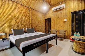 Une chambre d’hôtel comprenant un lit, une table de chevet, une chaise et une petite table avec des bouteilles d’eau.