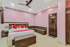 A hotel room with a bed, bedside tables, a bench, a wardrobe, and a ceiling fan. - Hotel O Royal (Rajnandgaon)