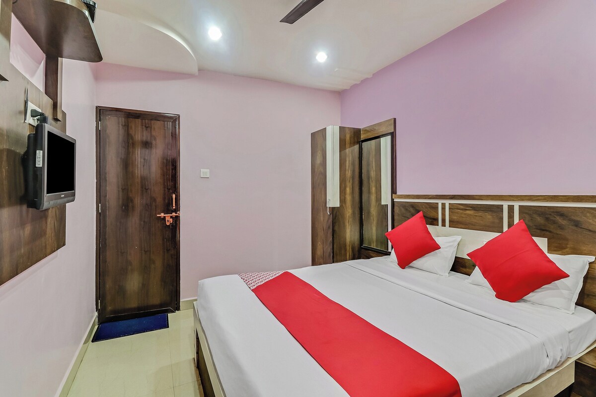 A hotel room with a bed, a television, a door, and a mirror.
