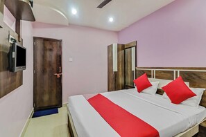 A hotel room with a bed, a television, a door, and a mirror. - Hotel O Royal (Rajnandgaon)