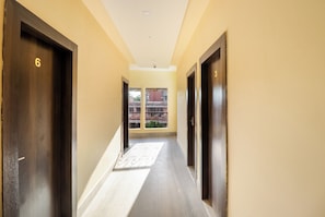 Un pasillo con puertas numeradas 3 y 6, que conduce a un espacio exterior con vista a un edificio.