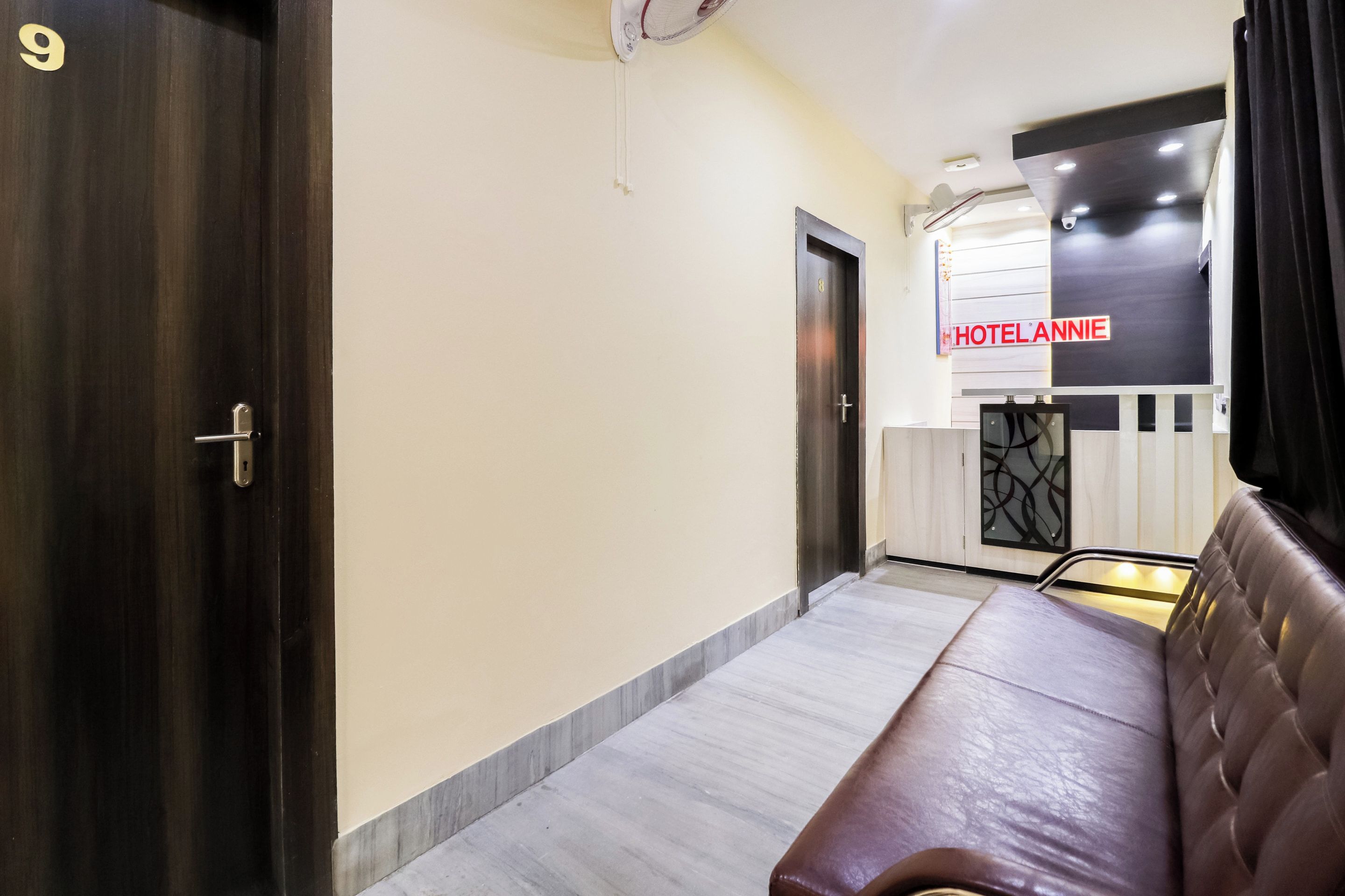 A hotel lobby with a reception desk, a sofa, and a door marked with the number 9.