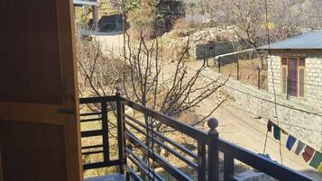 A balcony with a checkered floor, a railing, and a view of a mountainous landscape with buildings.