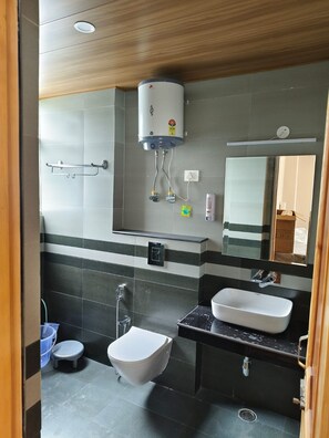Un baño moderno con inodoro, bidé, lavamanos y un perchero para toallas.