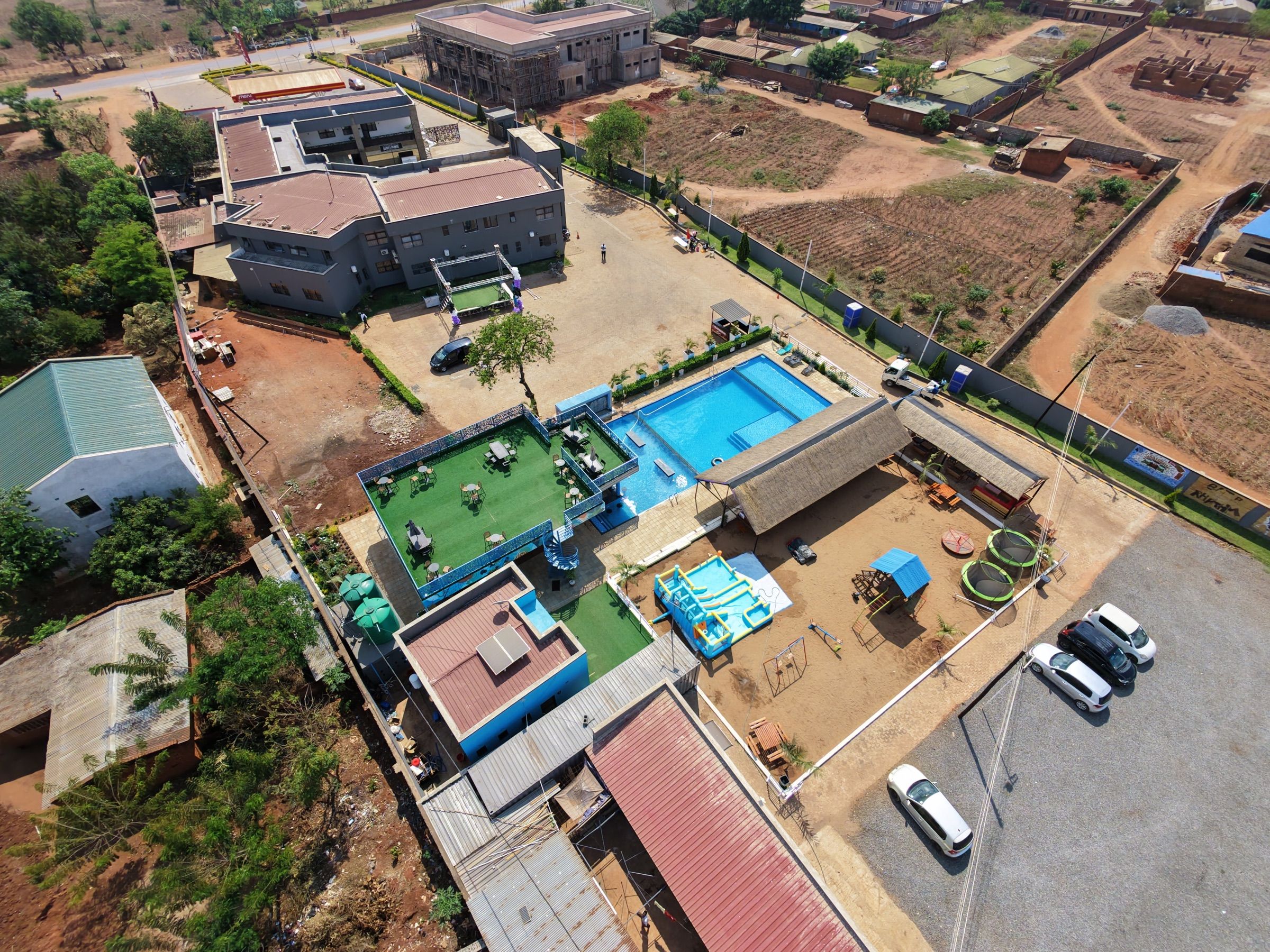 Vue aérienne d’un quartier résidentiel avec une piscine, une cour clôturée et différents bâtiments.