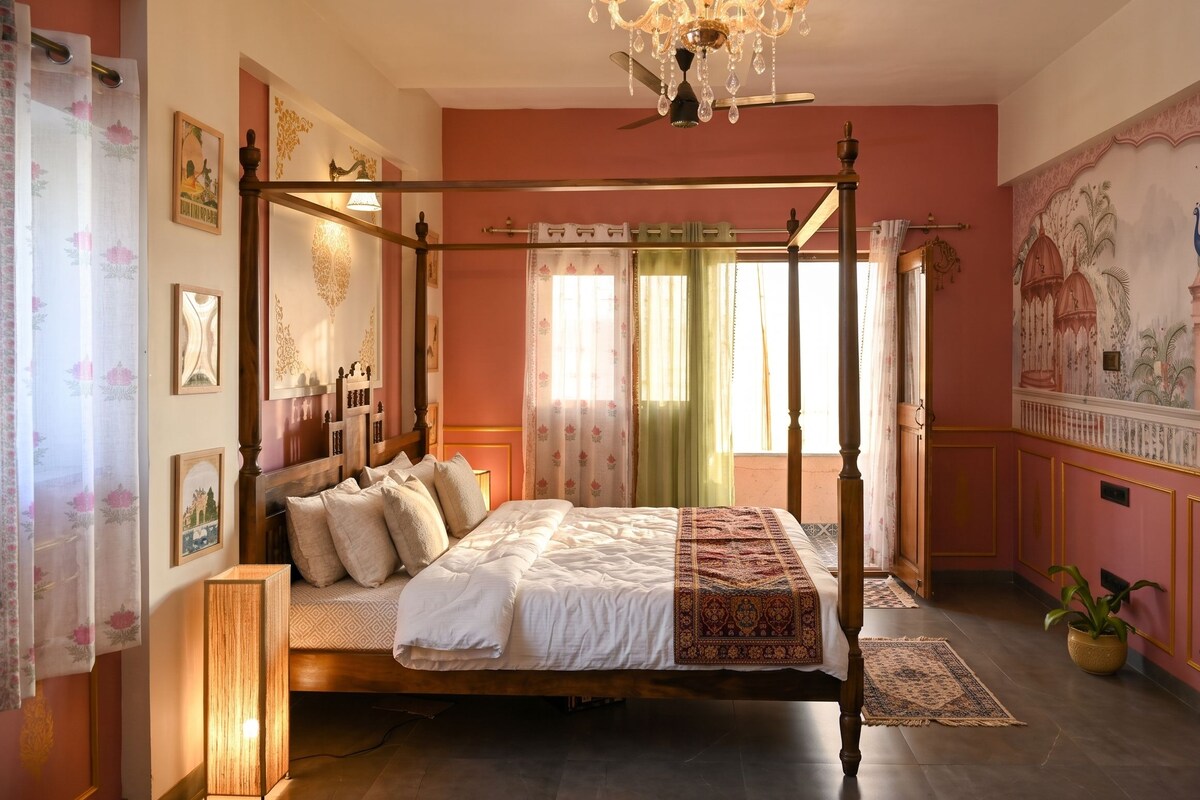 Een hemelbed met een baldakijn, een kroonluchter en een groot raam met gordijnen.