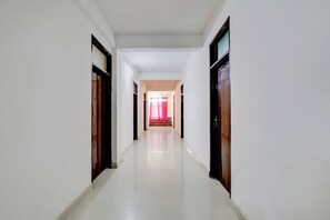 Un pasillo con paredes blancas y puertas que conduce a una habitación con cortina roja.