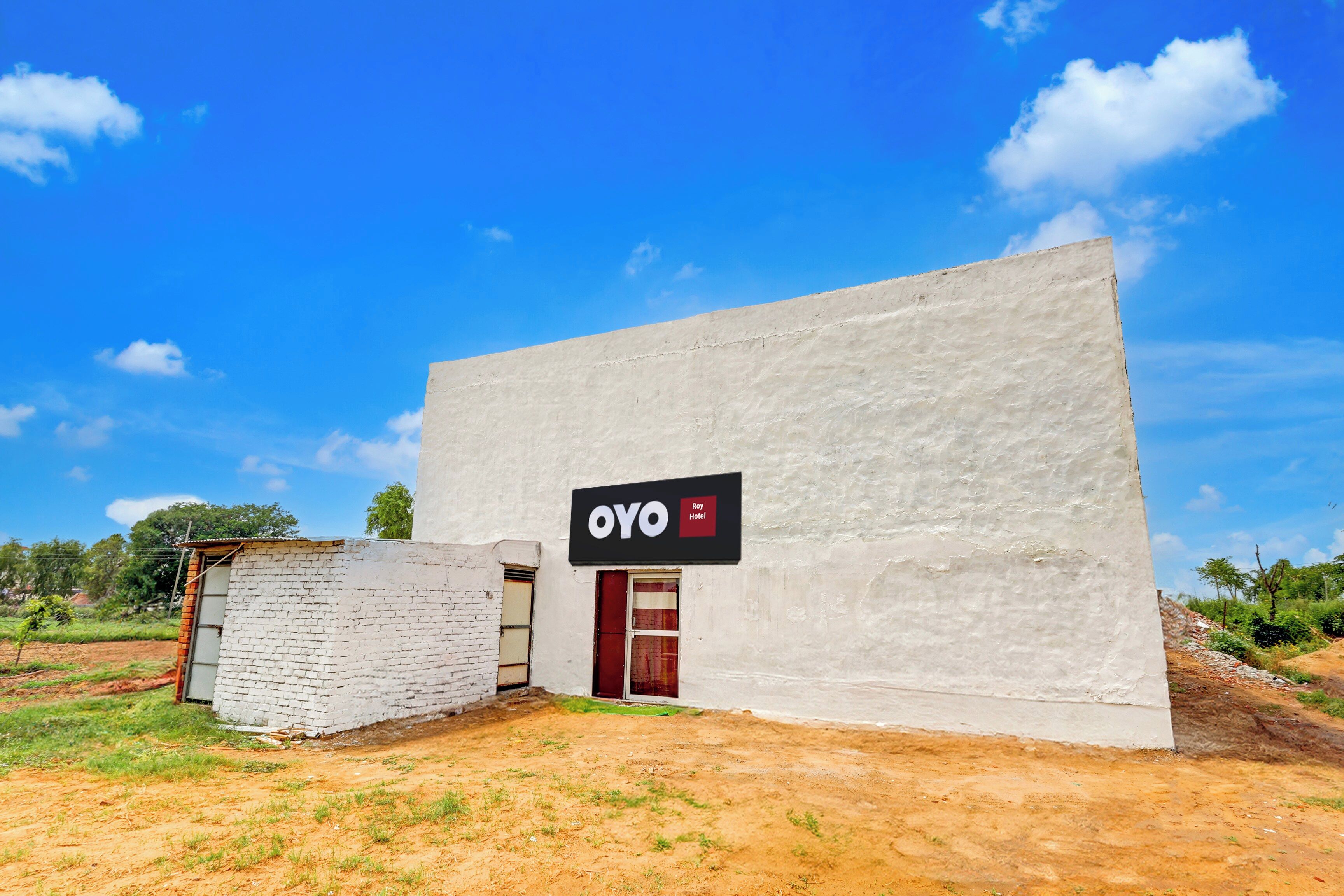 Um edifício com uma placa que diz 'OYO Roy Hotel' em uma parede branca.