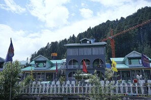 A hotel with a green roof, multiple windows, and a white picket fence in front. - The Saz Valley Resort (Bhaderwah)