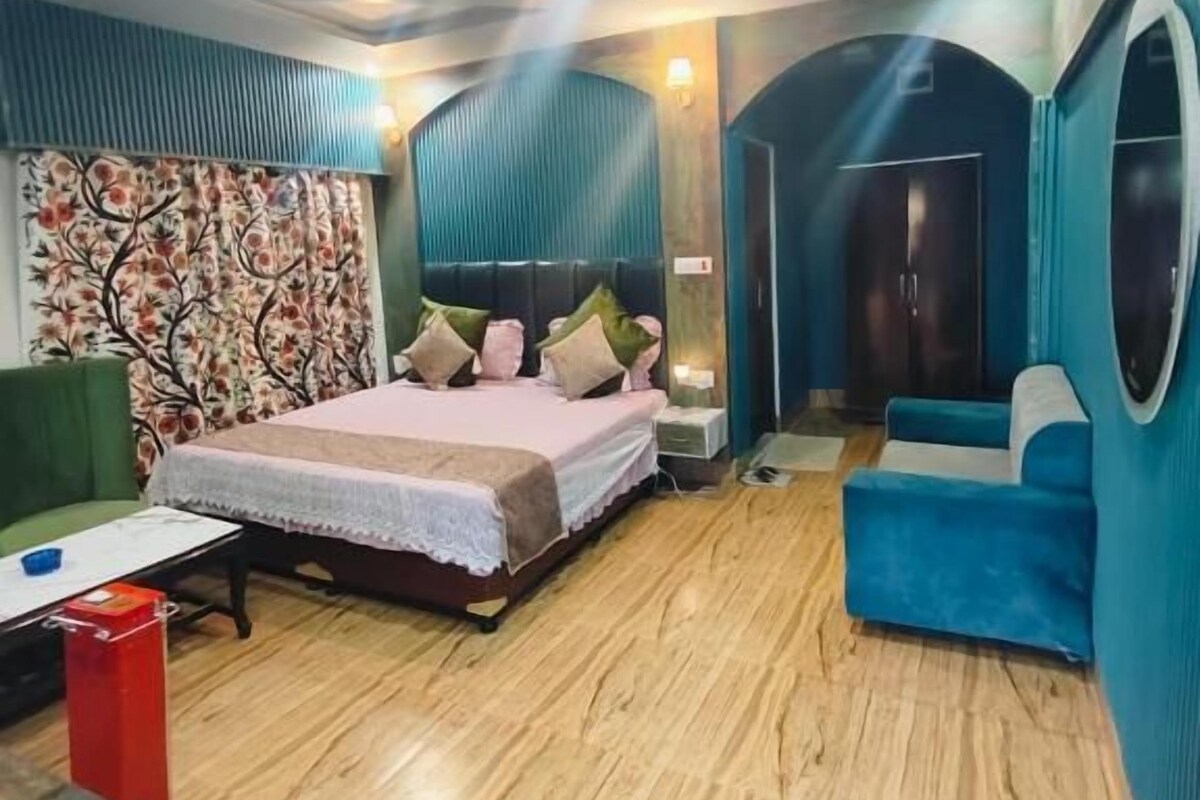 A bedroom with a bed, a sofa, a mirror, and a door.