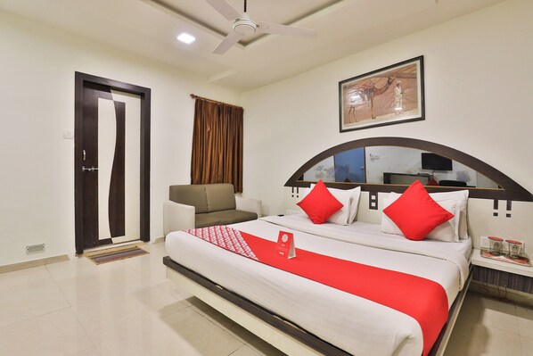 Habitación de hotel con cama, sofá, ventilador de techo, un cuadro y televisor.
