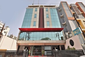Un hotel de varios pisos con una entrada destacada, un toldo rojo y un cartel para una fundación benéfica.