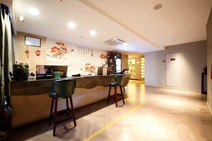 Uma área de recepção com balcão, dois bancos altos e uma parede com detalhes decorativos.
