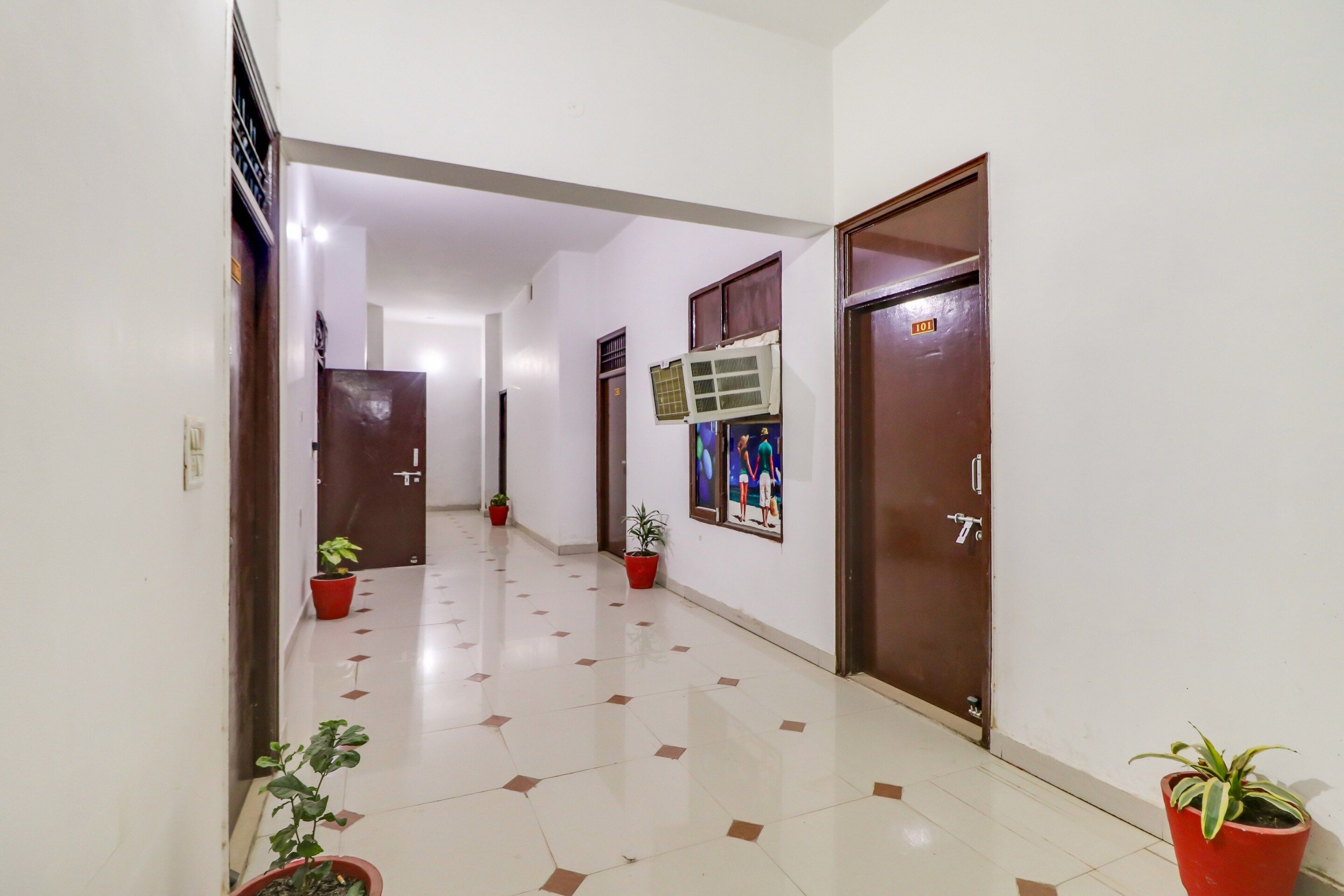 A hallway with tiled flooring, potted plants, and doors leading to rooms.