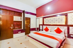 A bedroom with a bed, a wardrobe, a mirror, and a window with bars. - Hotel O Olive (Rohtak)