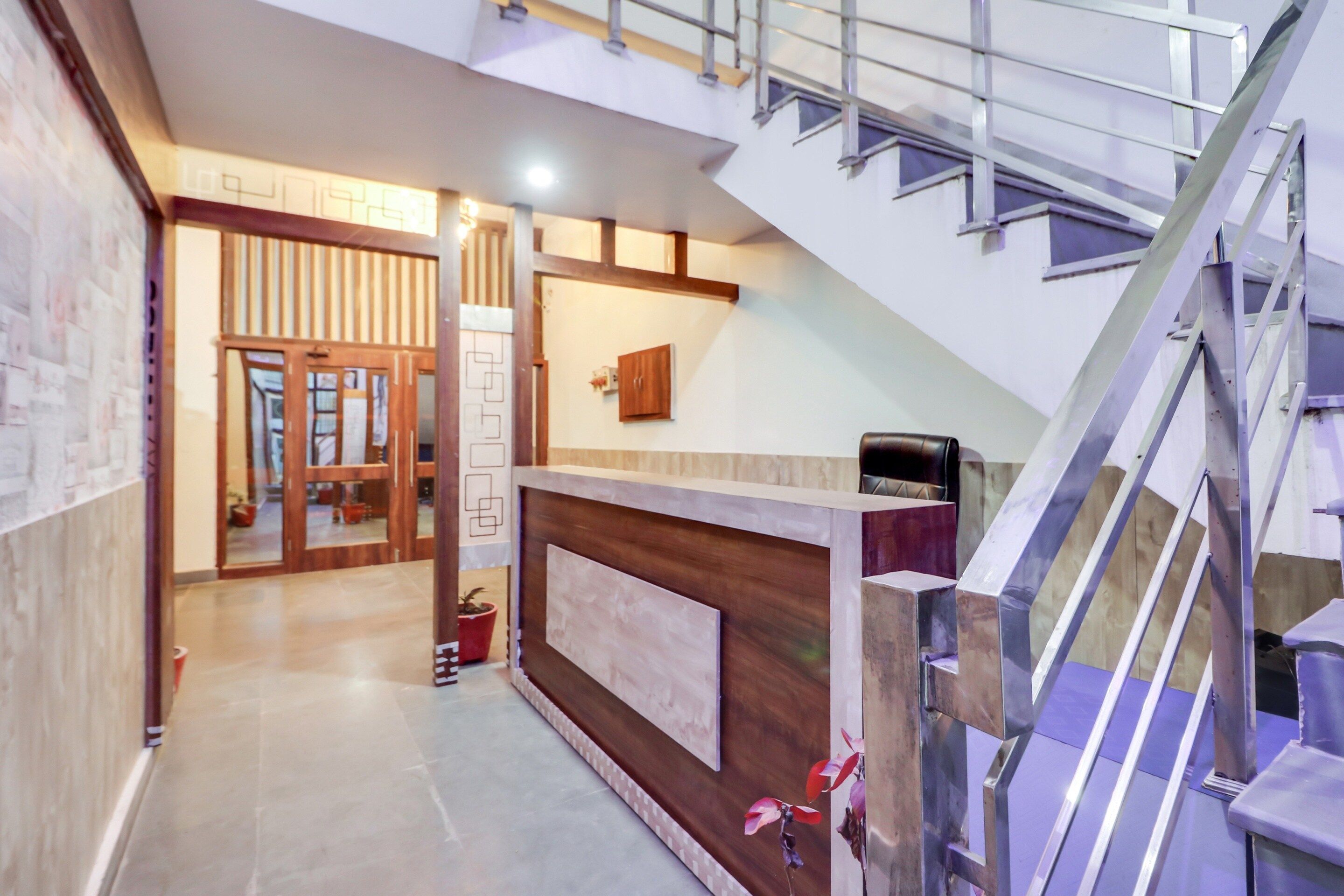 A hotel lobby with a reception desk, a staircase, and a view of the interior.