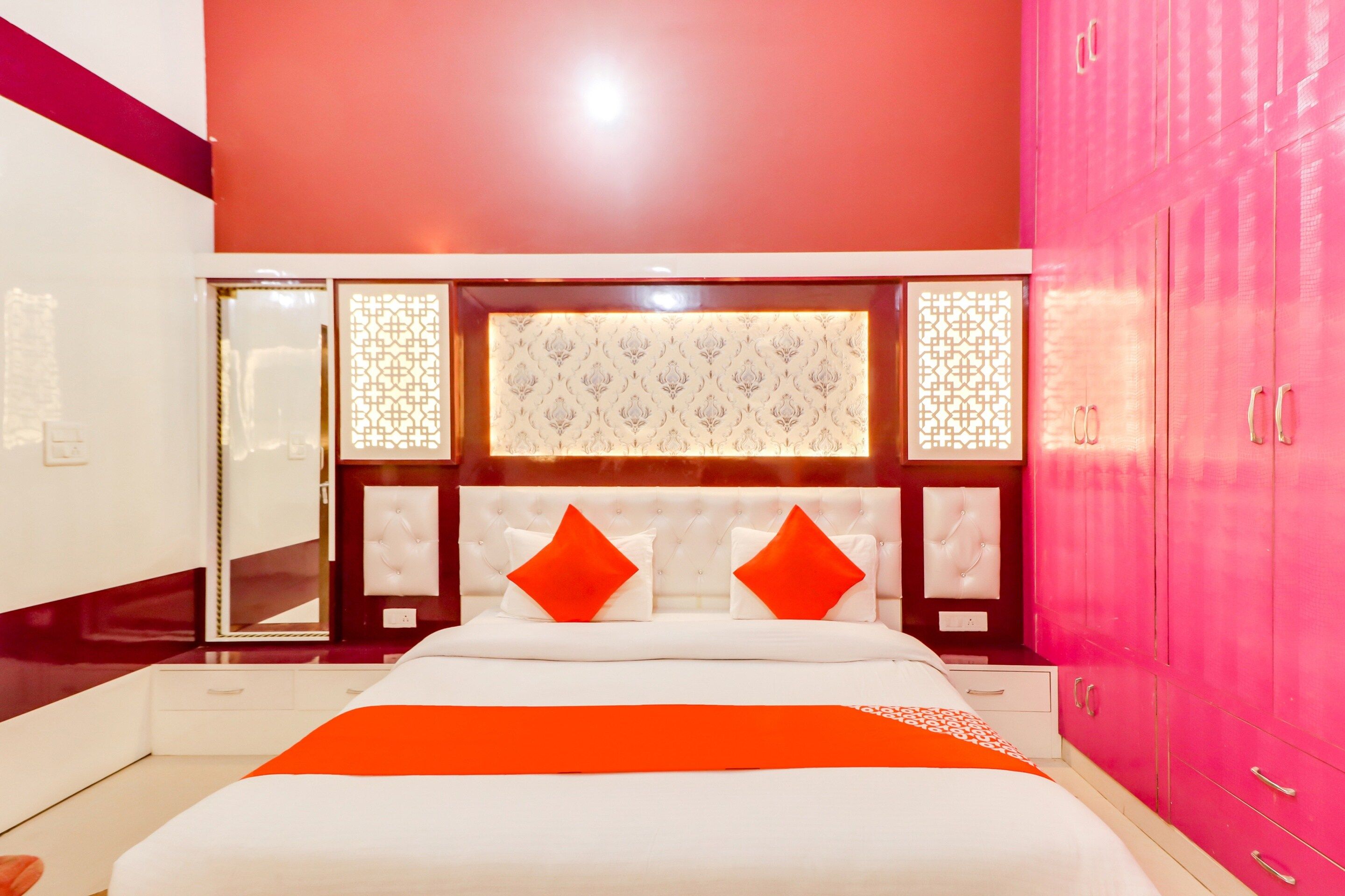 A bedroom with a bed, a mirror, a wardrobe, and a decorative panel.