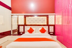 A bedroom with a bed, a mirror, a wardrobe, and a decorative panel. - Hotel O Olive (Rohtak)