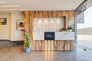 A reception desk with a marble top, wooden paneling, and a sign indicating the hotel name and room rates. - Hotel O by OYO Gold Inn (Rohtak)