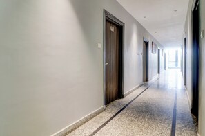 A long, narrow hallway with doors on one side and a carpeted floor. - Hotel O by OYO Gold Inn (Rohtak)