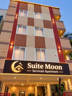 Um hotel com vários andares e uma placa com a inscrição 'Suite Moon Serviced Apartment'.