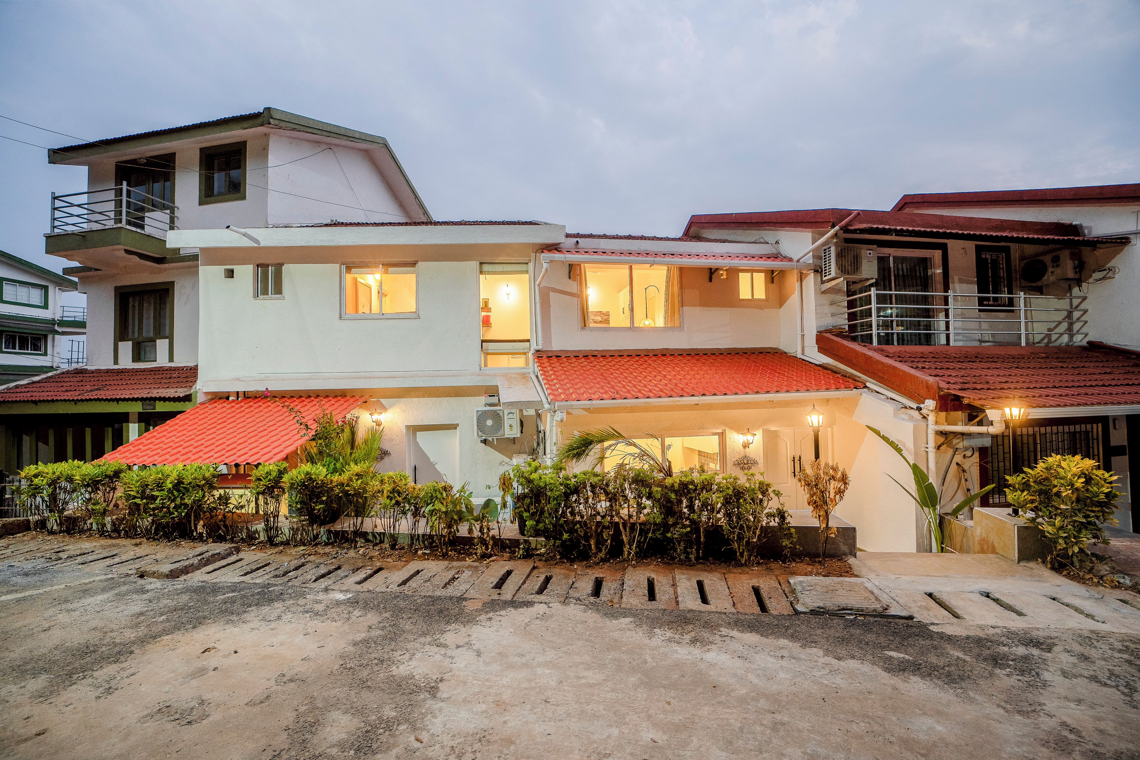 Um edifício residencial de dois andares, com telhado de telhas vermelhas, várias janelas e um aparelho de ar condicionado.